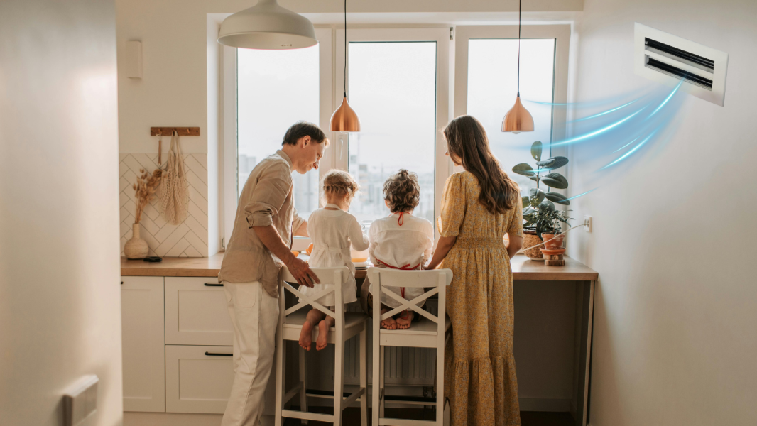Family in a bright, modern kitchen receiving clean airflow from a GREEN VENT grille, representing improved indoor air quality and comfort.