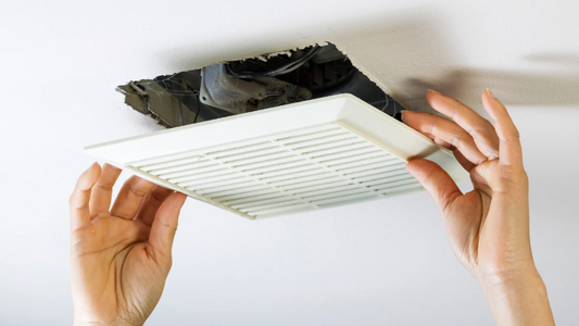 DIY maintenance: Hands holding a vent cover near its wall opening.