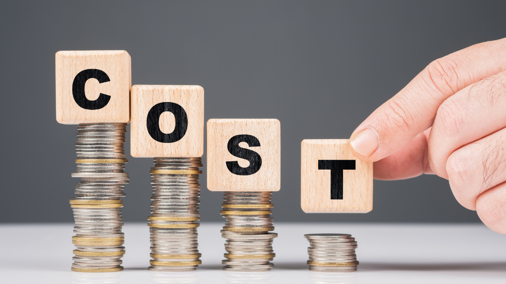 Visual representation of reducing costs: wooden blocks spelling 'COST' on decreasing coin stacks