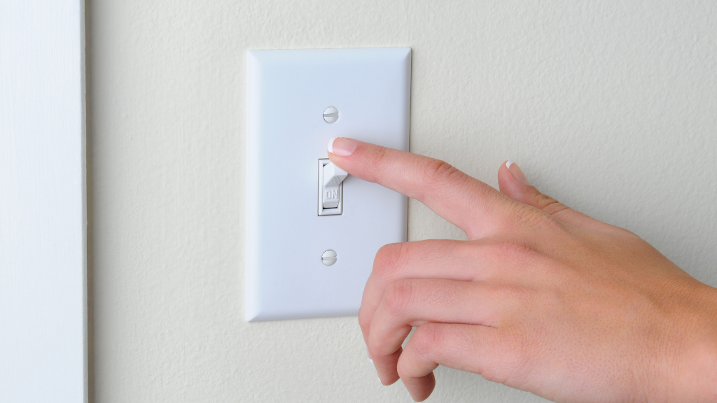 Close-up of a person's finger turning off a wall switch
