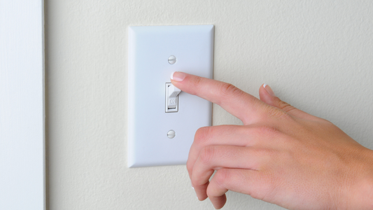 Close-up of a person's finger turning off a wall switch