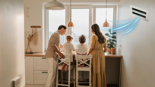 Family in a bright, modern kitchen receiving clean airflow from a GREEN VENT grille, representing improved indoor air quality and comfort.