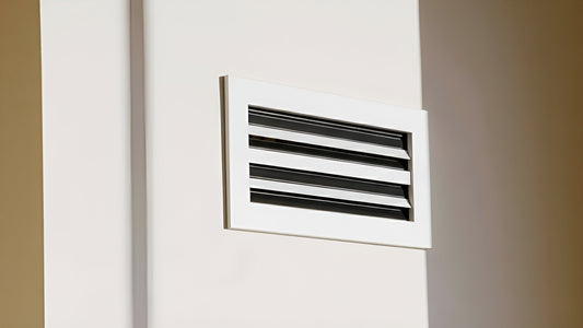 Close-up of a modern aluminum wall vent cover with sleek horizontal fins, installed on a clean white wall