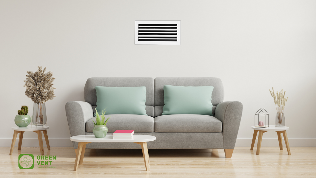 A white GREEN VENT linear slot diffuser is seamlessly installed on the wall above a gray sofa in a modern, minimalist living room