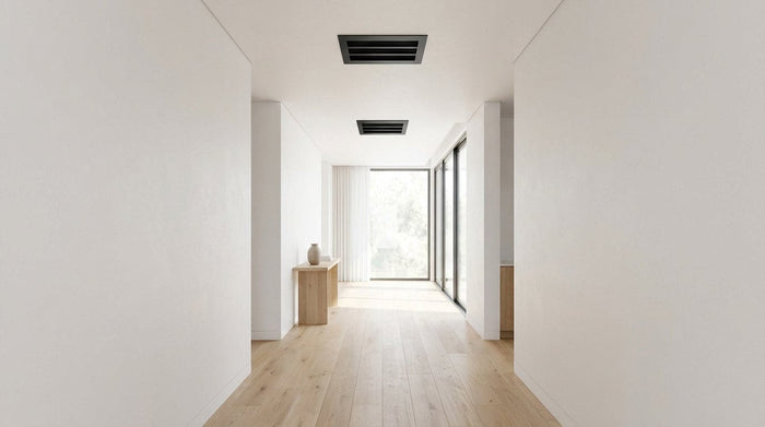 Two matte black linear slot diffusers in a modern hallway ceiling